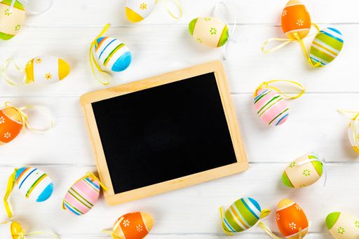 A top view of colorful easter eggs and a chalkboard with copy space