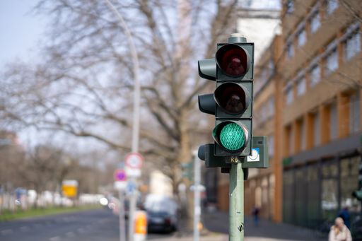A photo of traffic lights in a city with the green lamp on