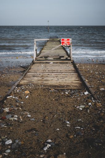 A vertical shot of a do not enter sign on a fence of a dock, written in both Welsh and English