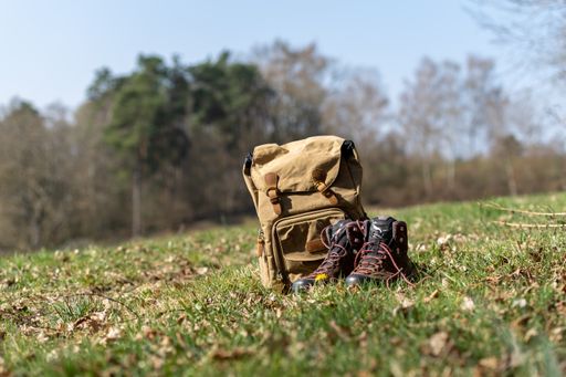 A closeup shot of a retro backpack and hiking boots in nature