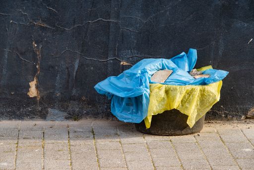 An old trash can with garbage and used mesh bags