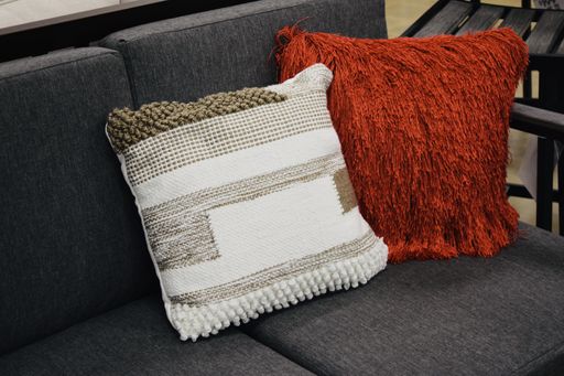 A two-seat couch with a red and a white and brown pillows