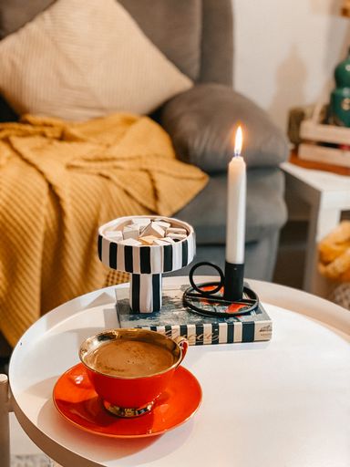 A vertical  of beautifully arranged a cup of coffee on a table decorated with a candle