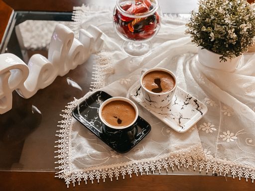A top view of beautifully arranged cups of coffee on a tablecloth decorated with flowers