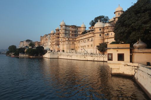 A wide shot of a beautiful building with domes near the water in Udaipur, India