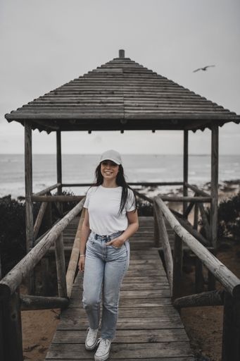 A beautiful front shot of a happy pretty Caucasian female on a wooden pier by the sea and a gray sky