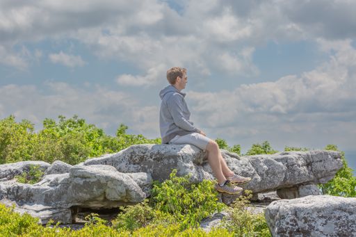 A beautiful shot of a young Caucasian man looking out at mountains at Bear Rocks in Dolly Sods Wilderness, West Virginia, United States