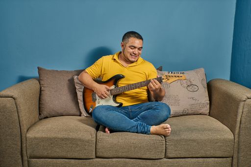 Singing and playing guitar at home on a relaxed couch