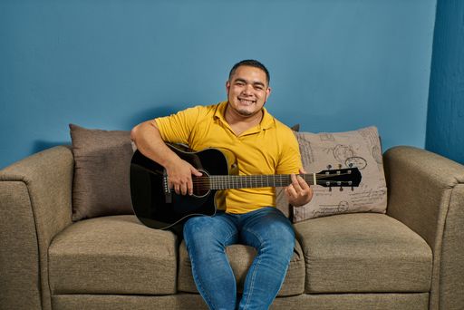 Singing and playing guitar at home on a relaxed couch