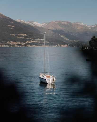 A vertical shot of a boat in a middle of a lake with mountains in the background during daytime