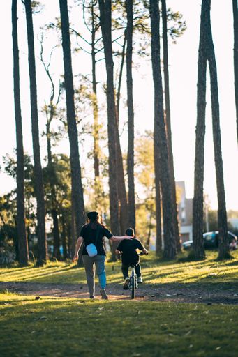 A beautiful shot of a Caucasian kid riding a bicycle and his mom walking next to him
