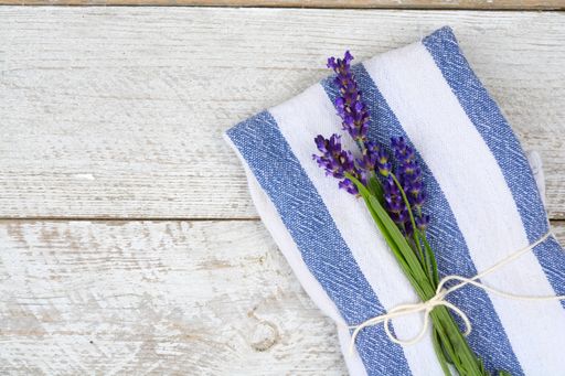 A high angle shot of a blue kitchen towel with Lavender flower isolated on the wooden surface
