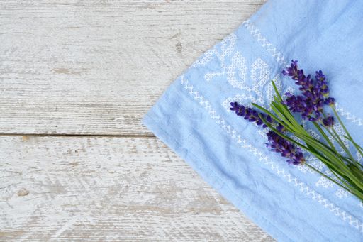 A high angle shot of a blue kitchen towel with Lavender flower isolated on the wooden surface