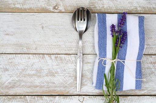 The silver cutlery and a blue-white kitchen towel with Lavender flower isolated on a wooden surface