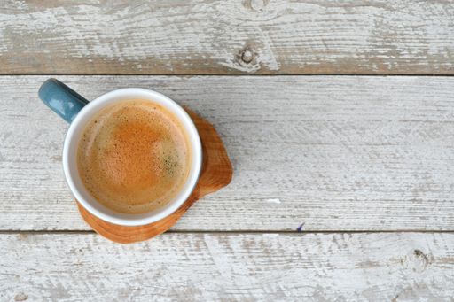 An overhead  shot of a cup of hot coffee isolated on the wooden surface