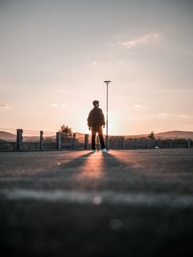 A vertical shot of a boy on a parkade at sunset
