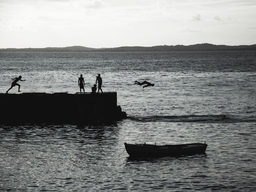 A scenic view of young people jumping from the pier of Porto da Barra in Bahia, Brazil