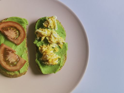 A high angle shot of tomato slices on one sandwich with guacamole and chicken on the other