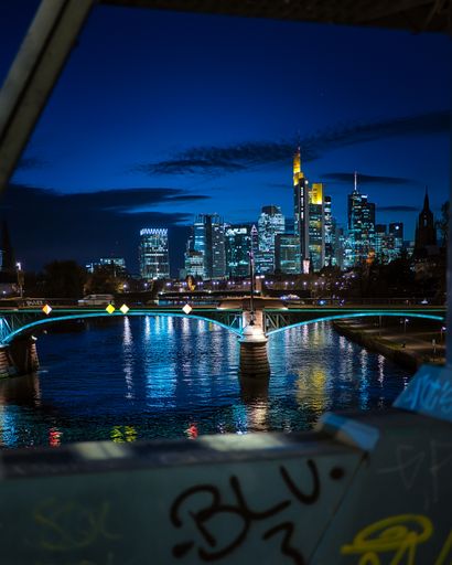 A vertical shot of the illuminated Frankfurt am Main skyline against a blue night sky