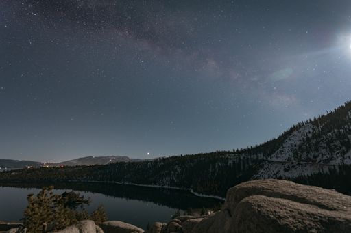 A beautiful view of a landscape with a lake and a forest under the starry sky