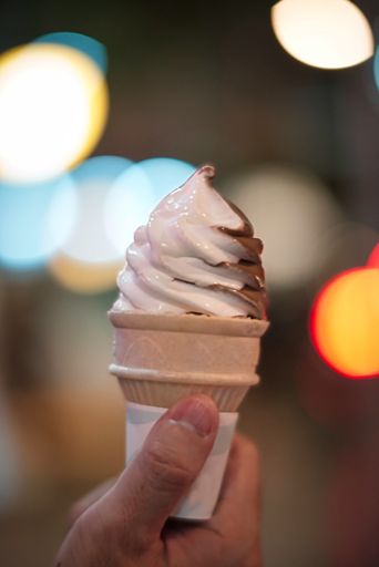 A selective focus shot of a hand holding a vannila and chocolate ice cream