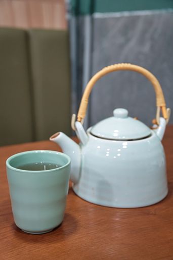 A selective focus shot of a teapot and a cup in a Cantonese restaurant