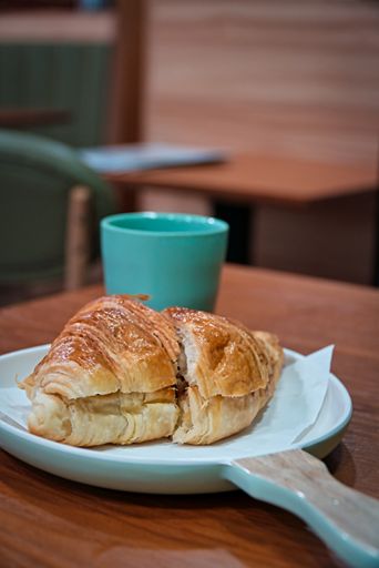 A selective focus shot of a delicious meat croissant and a tea cup in a restaurant