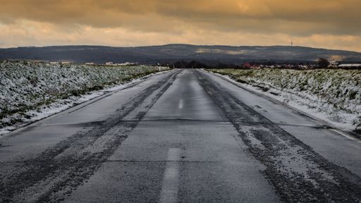 A chilling view of a snow-covered field and road in the countryside during sunset