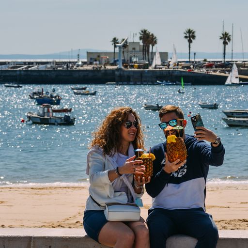 A closeup of a couple enjoying pineapple drinks next to the beach in Cascais, Portugal