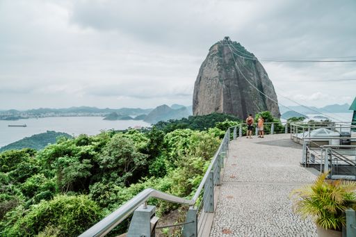Two tourists at Morro da Urca station with Sugarloaf Mountain in the background, Rio de Janeiro, Brazil