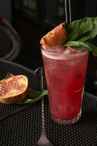 A vertical shot of pomegranate juice with black straw on table
