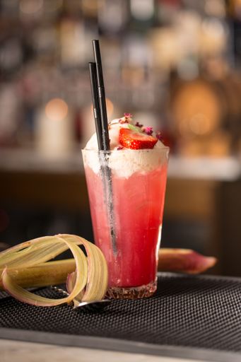 A vertical shot of strawberry cocktail with black straw on table