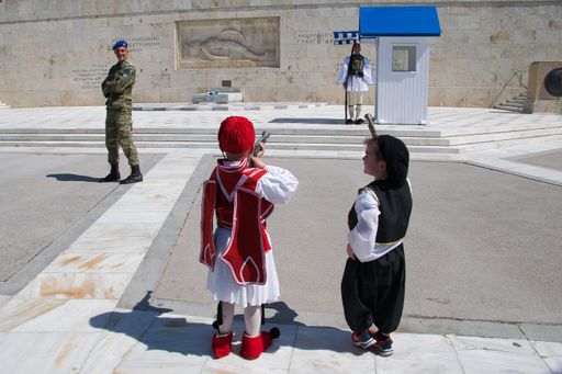 children in traditional Greek costumes look at the Soldier of the Presidential Guard, monument to the unknown Soldier ,Athens Greece March 25, 2022