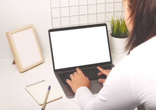 A back shot of female hands using laptop and mobile phone with a blank screen on the office