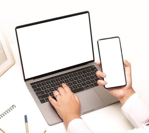 A closeup shot of female hands using a laptop and mobile phone with a blank screen on the office