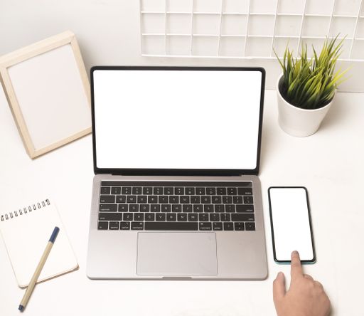 A top view shot of female hands using laptop and mobile phone with a blank screen on the office