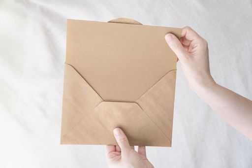 A person taking a brown document out of the envelope