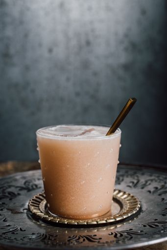 creamy drink cocktail with tamarind soda, nutmeg, cinnamon, cacao nibs, chocolate on wooden barrel with spoon