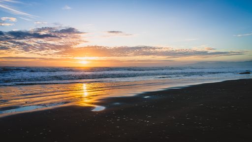 A scenic view of a beach in Christchurch, New Zealand during a beautiful sunset