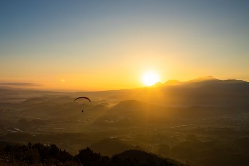A view of human flying with Paraglider over the mountains during sunrise