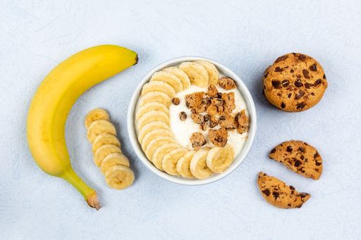 A top view of cream dessert with banana fruit in a bowl on blue background