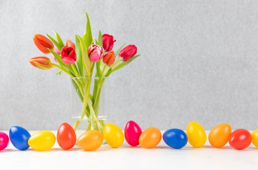 A closeup of a tulip bouquet in a vase near colorful easter egss