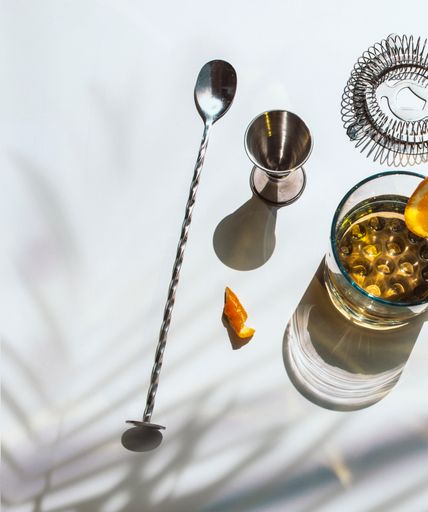 A vertical shot of barware for making cocktails with orange slices on a white background
