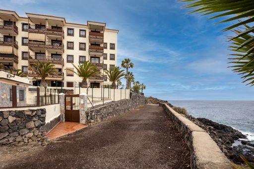 A scenic view of Amarilla beach in Tenerife with apartments in cloudy sky background