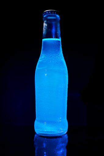 The bottle of blue water on the reflecting background