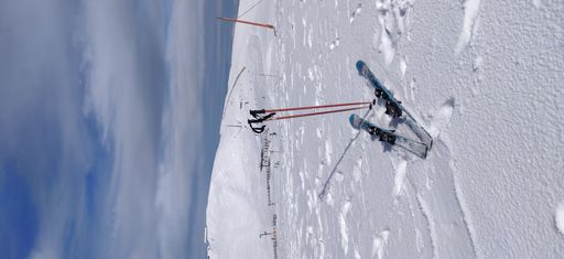 A vertical closeup shot of the skis and ski bindings on a snowy mountain on a cloudy day