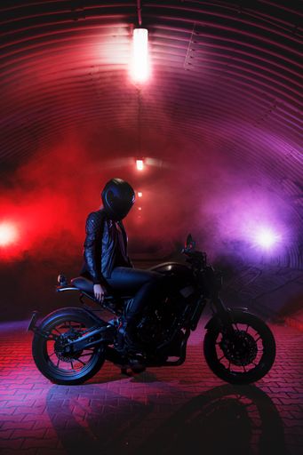 A vertical shot of a cool biker in a tunnel with vibrant lights and mist
