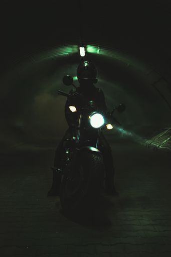 A vertical shot of a biker on his motorcycle in a dark tunnel