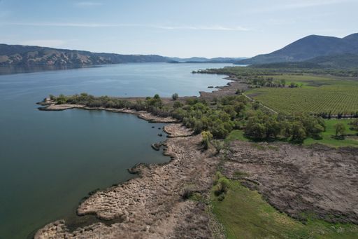 An aerial shot of a lake washing its shore covered with green forest on a slope of a mountain