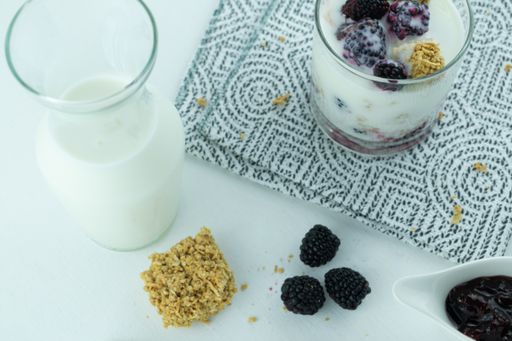 A top view of a glass of fresh parfait with blackberry and granola and blackberry jam on the table, healthy breakfast